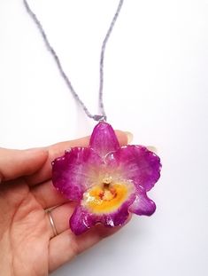 ☀️ Embrace the timeless beauty of orchids with this captivating handmade necklace! This exquisite necklace is more than just an accessory; it's a wearable work of art that captures the elegance and sophistication of orchids. Unlike traditional dried flowers, the orchid in this necklace is preserved in crystal-clear resin, ensuring its long-lasting beauty! Here's what makes this necklace truly special: Uniquely handcrafted: I cultivate and preserve the orchids myself, ensuring each necklace is a one-of-a-kind creation. You won't find another piece exactly like it! Even the flowers from the same orchid vary slightly in size and colour.  Timeless orchid design: The orchid's graceful silhouette and vibrant colors add a touch of sophistication and elegance to any outfit. Durable resin pendant: Unique Orchid-colored Jewelry Gift, Unique Orchid-colored Jewelry As A Gift, Unique Orchid Colored Jewelry For Gift, Unique Orchid Jewelry For Gift, Purple Flower Decorated Jewelry For Gift, Nature-inspired Purple Flower Jewelry, Purple Flower Nature-inspired Jewelry, Purple Jewelry With Flower Decoration As Gift, Purple Nature-inspired Flower Jewelry