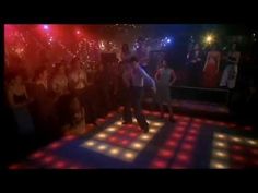 a group of people standing around a disco floor with colorful lights on top of it