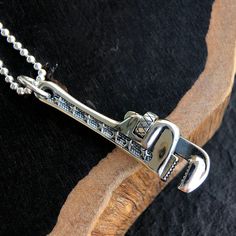 Men's Sterling Silver Pipe Wrench NecklaceThis unique men's jewelry piece is expertly handcrafted from solid sterling silver, ensuring both quality and durability. What sets it apart is its functional screw design, adding a touch of intrigue and playfulness. Embrace the industrial charm of this necklace, an expression of style and strength, making it the perfect choice for those who appreciate the extraordinary in every detail.Product DetailsMetal Type: 925 Sterling SilverGender: For MenStyle: PunkPendant Size: 14 mm (w) * 55 mm (h)Pendant Weight: 14.25 gChain Type: Sterling Silver Bead ChainChain Width: 2.5 mmLength: 18 in / 20 in / 22 in / 24 in / 26 in / 28 in / 30 in Silver Stainless Steel Jewelry With Custom Hardware, Silver Jewelry With Custom Hardware Gift, Silver Jewelry With Custom Hardware As Gift, Pipe Wrench, Unique Necklace, Necklace For Men, Sterling Silver Mens, Men's Jewelry, Sterling Silver Bead