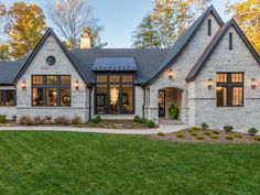 a large brick house with lots of windows on the front and side of it, surrounded by lush green grass