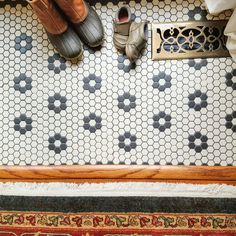 two pairs of shoes sitting on top of a tiled floor next to a shower stall