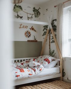 a white bed sitting under a window next to a wooden frame with palm trees on it