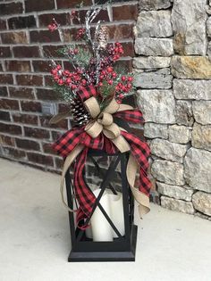 a candle with a red and black bow on it sitting in front of a brick wall