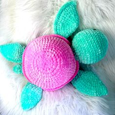 a pink and blue stuffed animal laying on top of a white rug