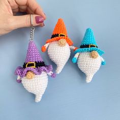 three crocheted gnome key chains being held by a hand