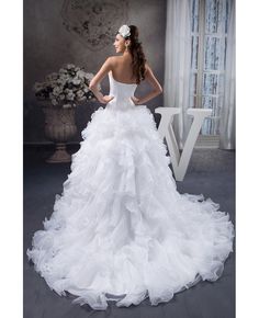 a woman in a white wedding dress standing on a gray floor with her back to the camera