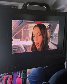 a television screen in the back seat of a car with a woman's face on it