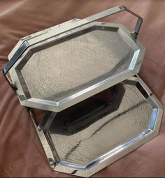 two mirrored trays sitting on top of a bed