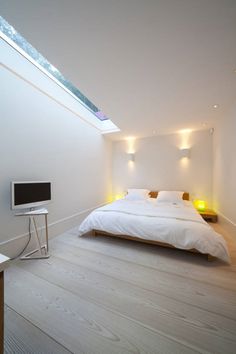 a bed sitting under a skylight in a bedroom next to a desk and chair