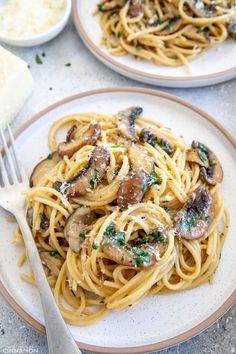 two plates of pasta with mushrooms and parmesan cheese on them, ready to be eaten