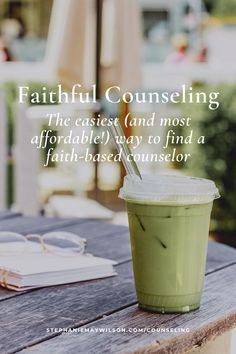 a green drink sitting on top of a wooden table next to an open book and umbrella