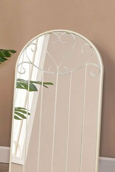 a white mirror sitting on top of a wooden floor next to a potted plant