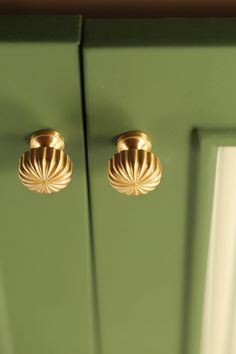 two brass knobs on the front of a green cabinet