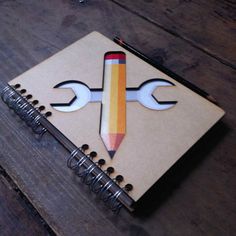 a notebook with a pencil in the shape of a cross and two wrenches on it