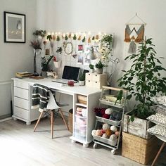 a white desk topped with a laptop computer next to a potted plant and other items