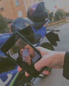 someone taking a selfie with their cell phone in front of a parked motorbike