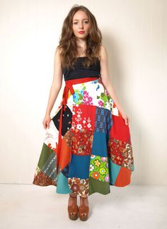 a woman standing in front of a white wall wearing a multicolored patchwork skirt