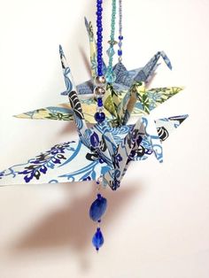 an origami bird hanging from a chain with beads and necklaces on it