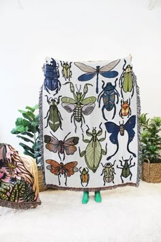 a blanket with bugs on it sitting next to potted plants