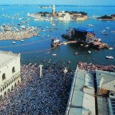 an aerial view of a crowded city with boats and people on the water in front of buildings