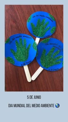 three handprinted paper fans with green grass on them sitting on top of a wooden table