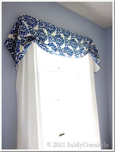 blue and white curtains hanging on the side of a window