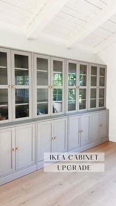 an empty room with wooden floors and gray cabinets in the center, there is a large window on the far wall