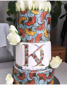 a multi - tiered cake decorated with flowers and the letter k on it's side