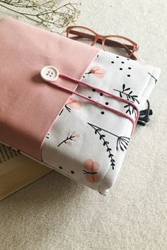 a pair of glasses sitting on top of a pink and white cloth covered in flowers