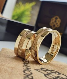 two gold wedding rings sitting on top of a table