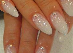 a woman's nails with white and gold glitters