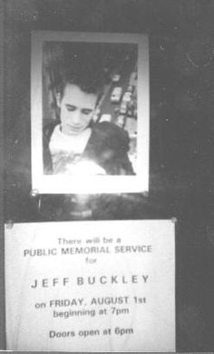 a black and white photo of a person holding a dog in front of a public memorial service sign