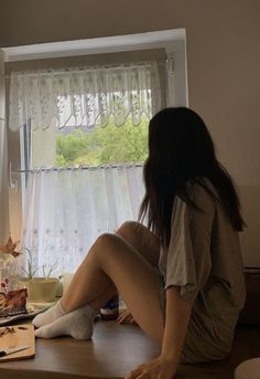 a woman sitting on top of a table next to a window