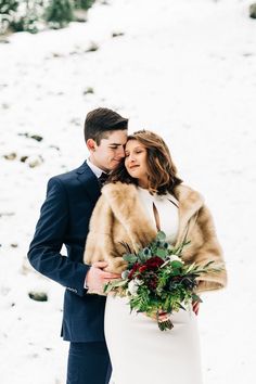 a bride and groom standing in the snow