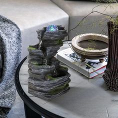 a table topped with vases filled with plants and water pouring out of them on top of books