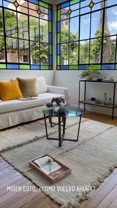 a living room with stained glass windows and white furniture in the corner, along with a rug on the floor