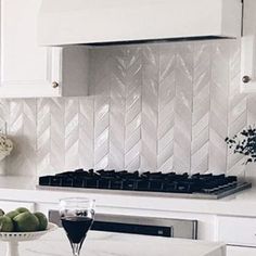 a kitchen with white cabinets and marble counter tops, an oven hood over the range