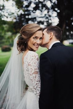 a bride and groom kissing in front of trees