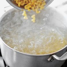 a pot full of macaroni and cheese being stirred by a ladle with water