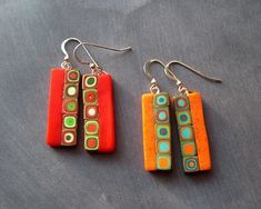 two pairs of earrings with colorful designs on them sitting on a table next to each other