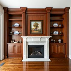 an empty living room with wood paneling and built - in bookshelves on either side of the fireplace