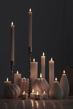 many candles are lit on a table in front of a black background with one candle surrounded by smaller ones