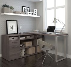 a computer desk with a laptop on top of it next to a chair and window