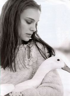 a woman is holding a white swan in her hands and looking down at it's neck