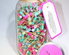 a jar filled with lots of colorful sprinkles next to a pink tag