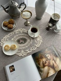 an open book sitting on top of a table next to two cups and saucers