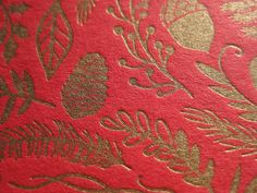 a red and gold wallpaper with floral designs on the back side is seen in this close up photo