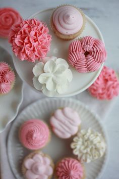 some pink and white cupcakes on plates