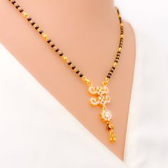 This 22k gold Mangal Sutra, weighing 9.9 grams, radiates festive charm with its stunning combination of black beads and cubic zirconia stones. The necklace measures 18" in length with a 1.5" drop, and adjustable 1" links offer a flexible fit. Finished in yellow gold, its hook lock ensures secure wear while adding to its elegance. Ideal for special occasions, this piece captures the perfect blend of tradition and sparkle, making it a dazzling addition to your jewelry collection. PRODUCT DETAILS Gold Purity(karat): 22k Item Weight(grams): 9.9 Item Finish: Yellow Gold Stone: Black Bead + Cubic Zirconia Necklace Length: 18" Drop Length: 1.5" Adjustable Links: 1" Links Lock Style: Hook Lock Elegant Black Temple Necklace As Gift, Elegant Black Temple Necklace Gift, Festive Black Necklace In 22k Gold, Festive Gold Necklace With Black Beads, Festive Gold Necklaces With Black Beads, Black 22k Gold Necklace For Weddings, Black 22k Gold Jewelry As A Gift, Black 22k Gold Jewelry Gift, Black 22k Gold Jewelry For Wedding