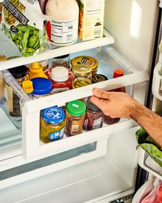 a man is reaching into an open refrigerator to pick up some food from the freezer